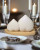 Two heart-shaped white salt and pepper shakers on a bamboo stand, perfect for wedding favors and charming table decor.
