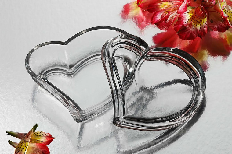 A clear crystal heart on a table surrounded by colorful flowers, perfect for wedding or bridal shower favors