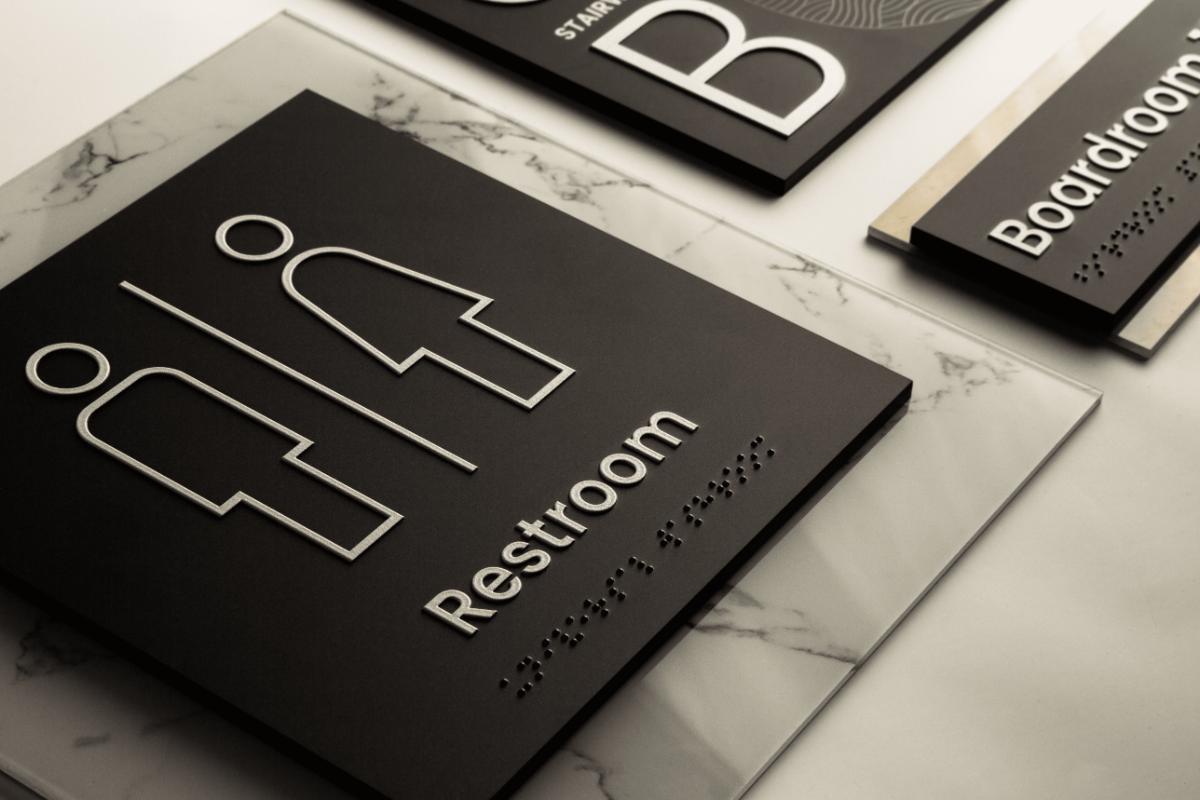Singularum restroom and boardroom signs with tactile pictograms and Braille on a marble surface
