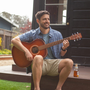Man sitting on deck with guitar wearing Weston Supersoft Crew Neck Tee in light blue
