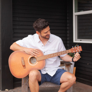 Man sitting outside tuning guitar wearing Daxton Spread Collar Shirt White