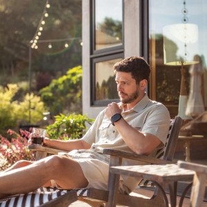 Man sitting in chair outside wearing Liam Pearl Snap Printed Shirt in Pistachio Shell