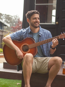 Man sitting outside plaing guitar wearing Hawke Organic Cotton Shirt in midnight blue