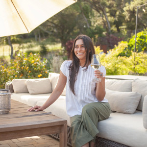 Woman sitting on couch outside wearing Pippin Pintuck Top in White