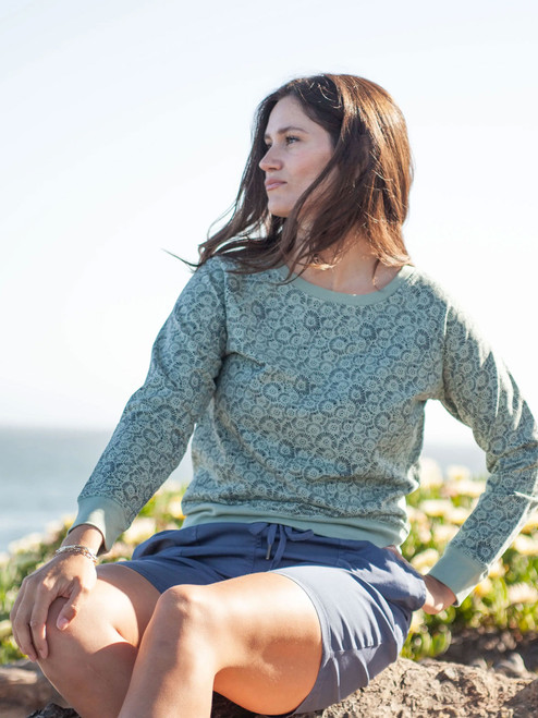 Woman sitting outdoors near ocean wearing Inola Raglan Sleeve Printed Sweatshirt in Jadeite Green