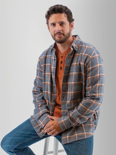 Man sitting on stool wearing the Chase Organic Cotton Flannel Shirt in blue fog plaid.