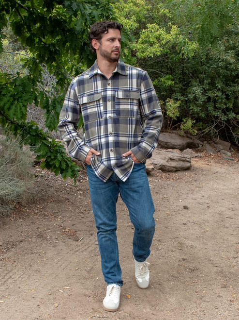 Man walking on dirt road wearing the Redwood Fleece Plaid Shirt in olive green plaid.