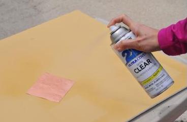 picture of person spraying a clear cloat on copper