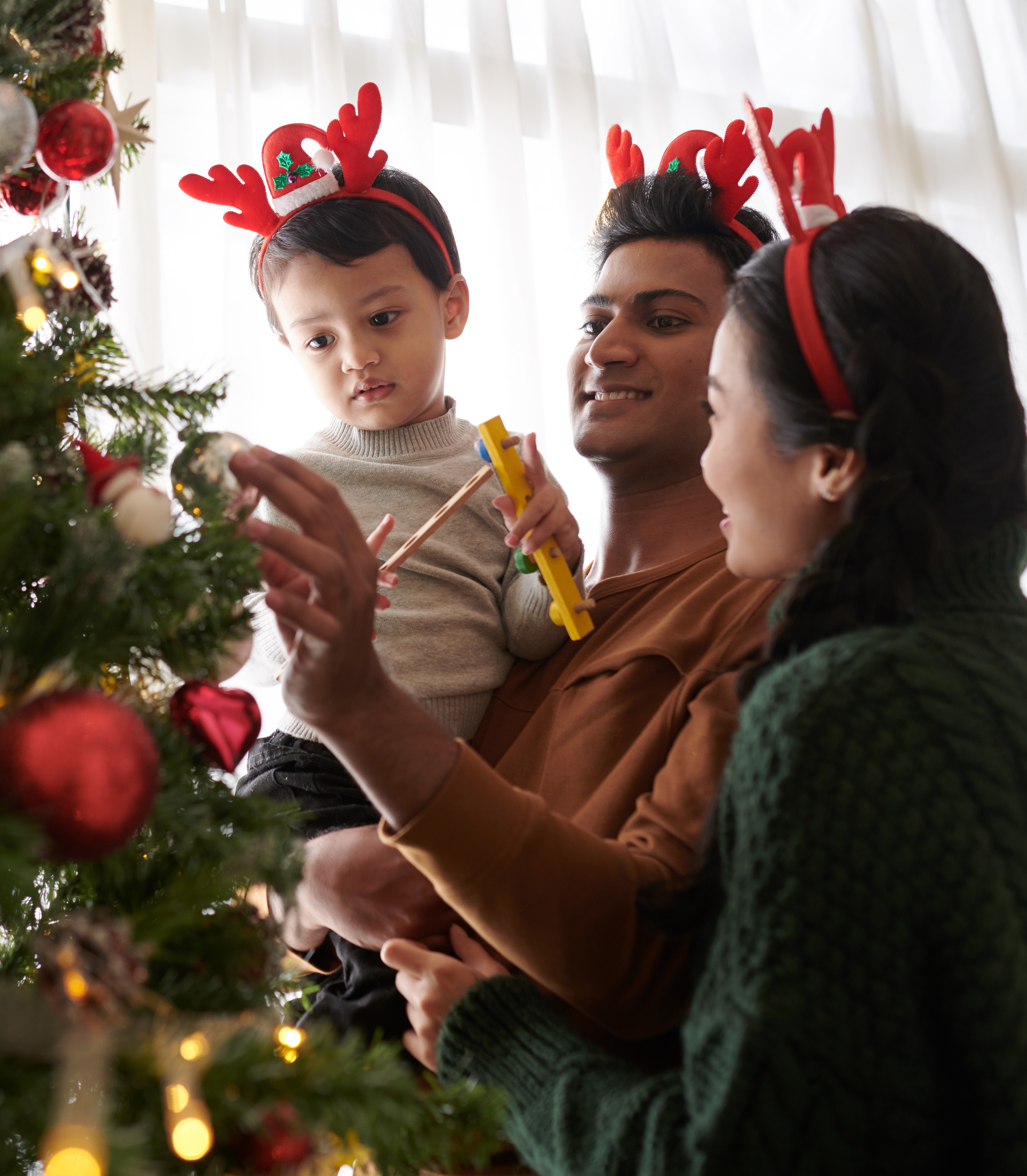 father, mother and son putting decoration on christmas tree 