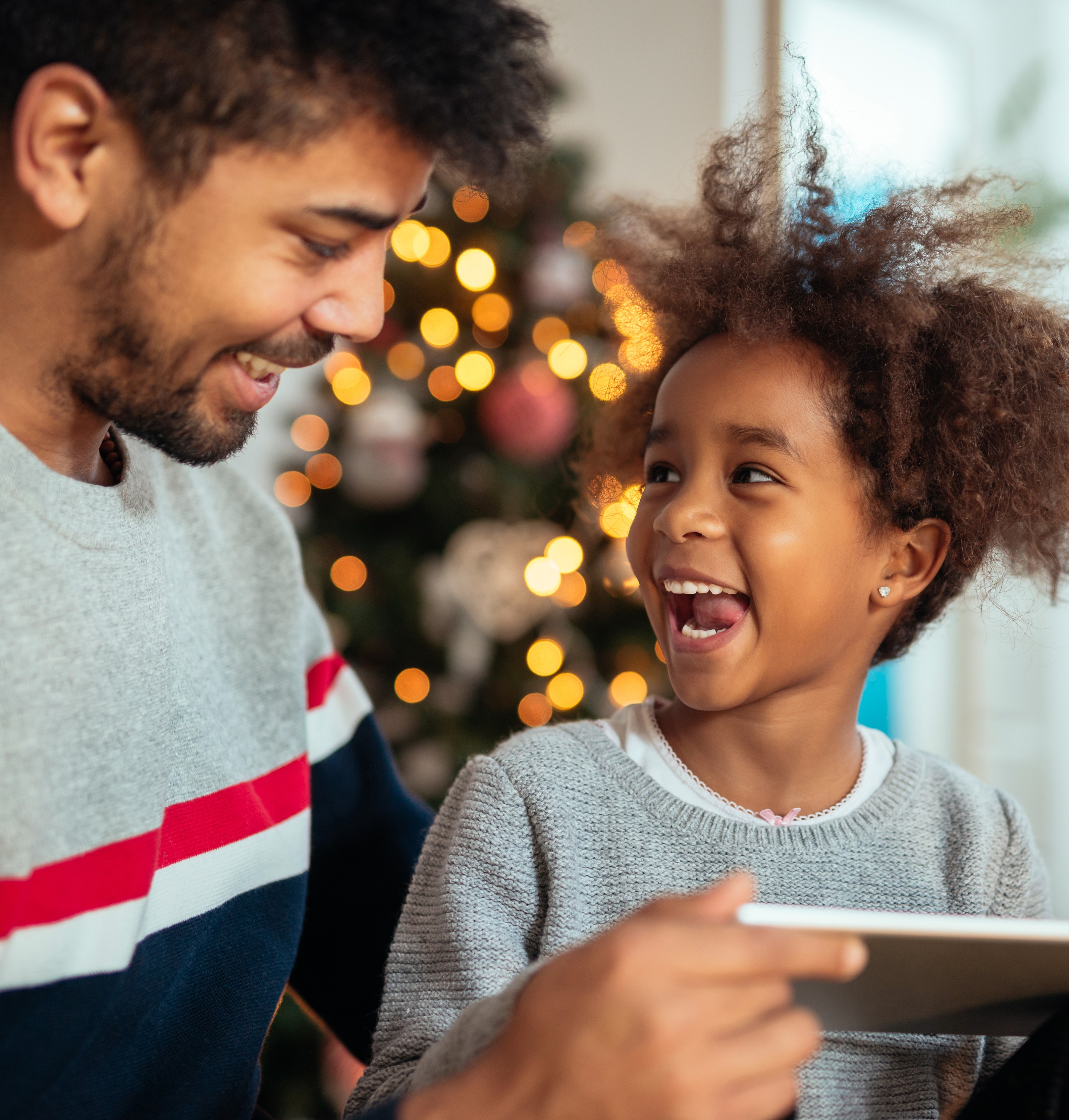 father and son smiling with christmas tree in background