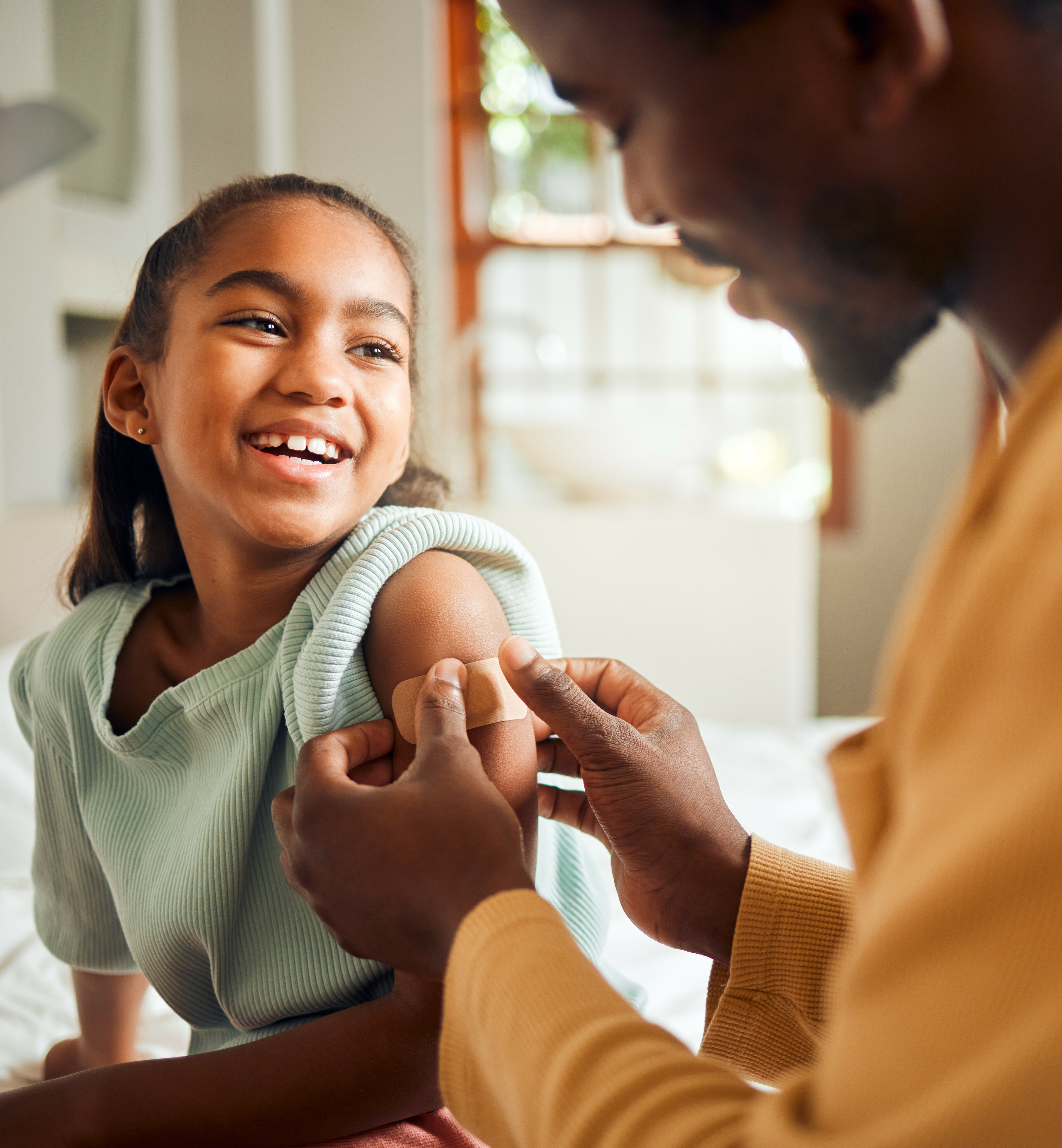 Father putting plaster on daughters arm