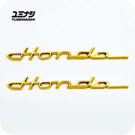 YUMINASHI GOLD FLEXIBLE ABS LOWRIDER LOGO SET S600/S800 (2PCS/SET) FOR DAX, TRAIL & CHALY (75700-098-000G)