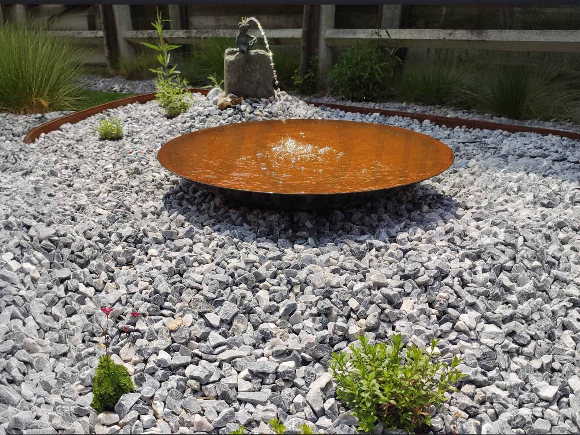 Moderne cortenstalen waterschaal in een grindtuin met siergrind en waterornament, geleverd door Godu voor een stijlvolle tuin inrichtingsoplossing.