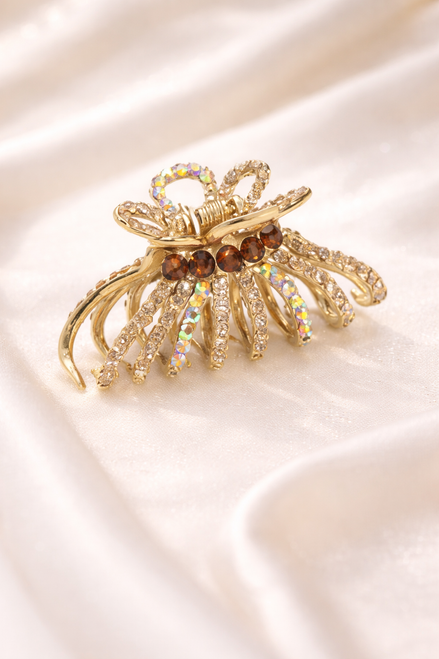 Luxe Arc Crystal Hair Claw: gold-coloured openwork claw set with crystals on cream fabric