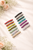 Éclat Classic Mini Crystal Barrette colour range: sixteen small flower-bead barrettes in rows of many colours on pale fabric