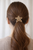 Aurelia Bloom Crystal Hair Tie worn in hair: back view of a low ponytail secured with a gold-tone crystal flower