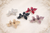 Five flower-shaped hair clips in clear, black, red, pink and amber on white fabric with bead trim