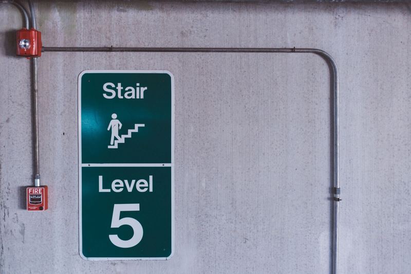 Fire alarm pull station and horn strobe on a concrete stairwell wall