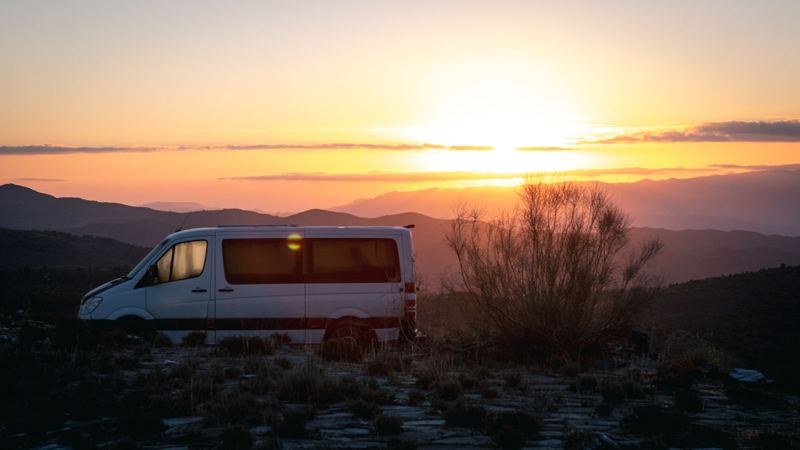 Camper van parked on a mountain ridge at sunset