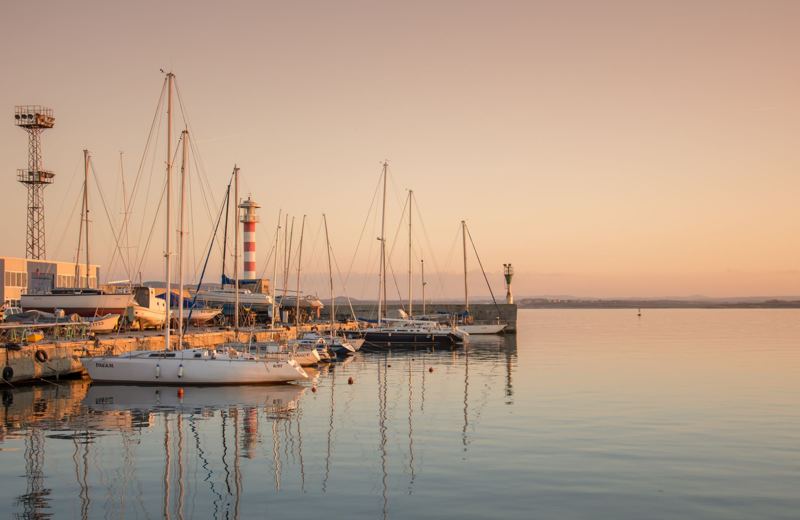 Sailboats moored in a calm marina at golden hour