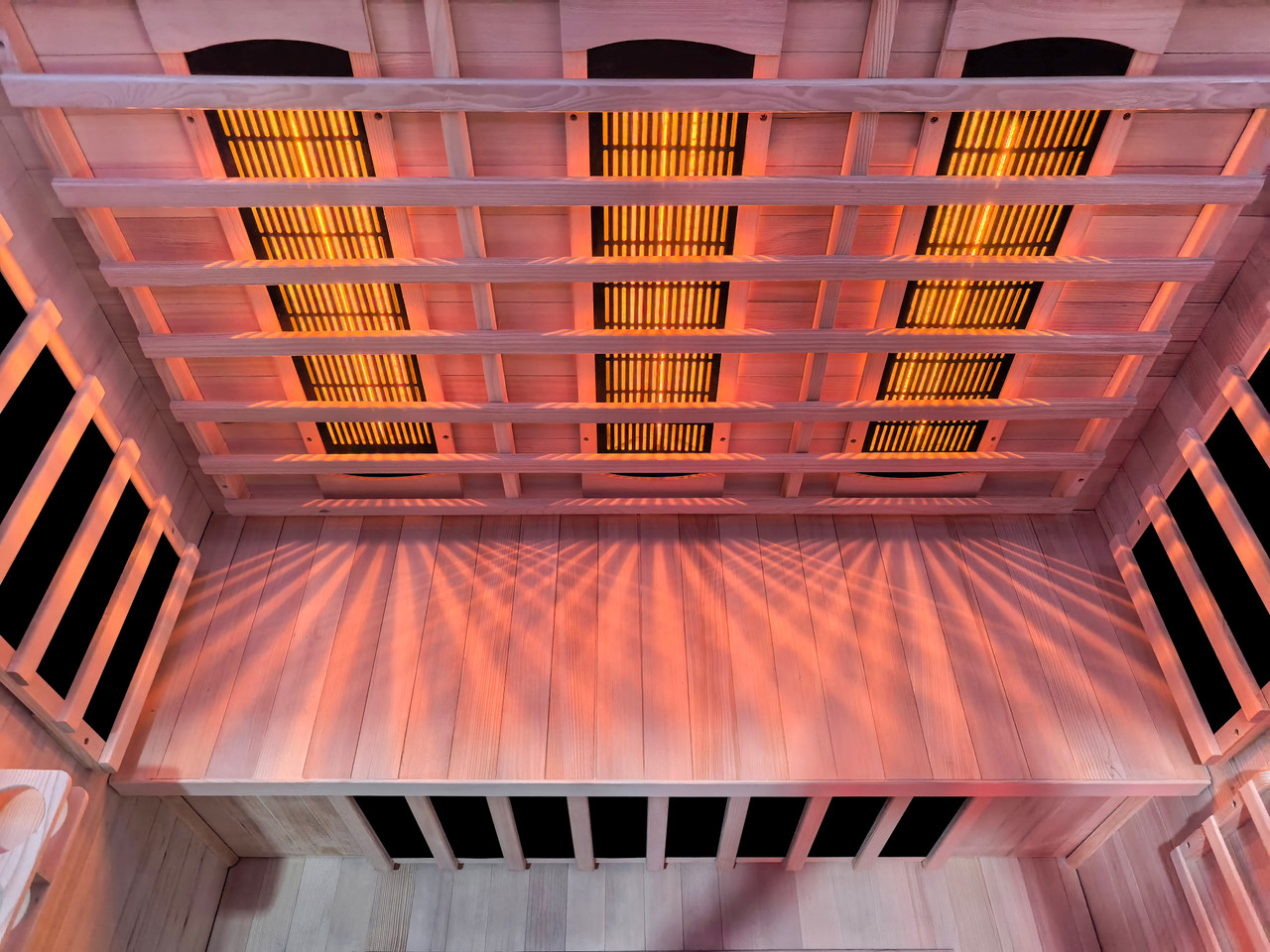 Room for everyone, warmth for all. The Vista Trio's expansive hemlock bench sits beneath three glowing overhead infrared rod heaters — casting deep, even heat across every seat in the cabin.