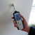 Sper Scientific Scanning Moisture Meter, person holding digital moisture tester against a wall to measure surface moisture levels.