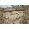 Spectra Precision LL1505C rotary laser on a tripod beside a formed footing excavation, holding elevation for a concrete foundation pour