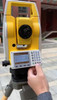 Northwest Instruments NTS03 total station on a tripod at a jobsite, operator pressing the alphanumeric keypad with the LCD angle display showing