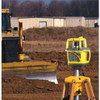Spectra GL700 series rotary laser set up on a tripod on a construction site, with a motor grader working to grade behind it