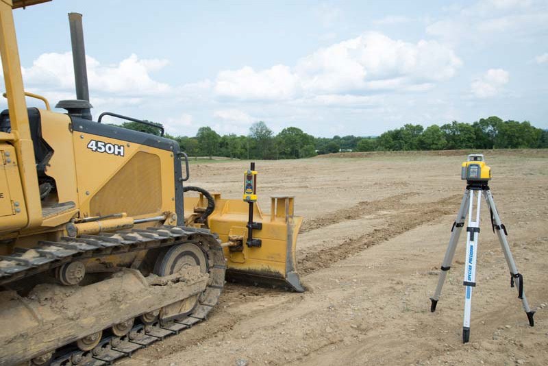 Dozer with a laser machine receiver on its blade mast and a Spectra laser on tripod