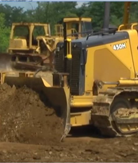 Crawler dozer pushing dirt with a laser machine receiver on its blade mast