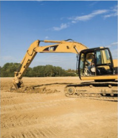 Yellow CAT excavator digging to grade on an open construction jobsite