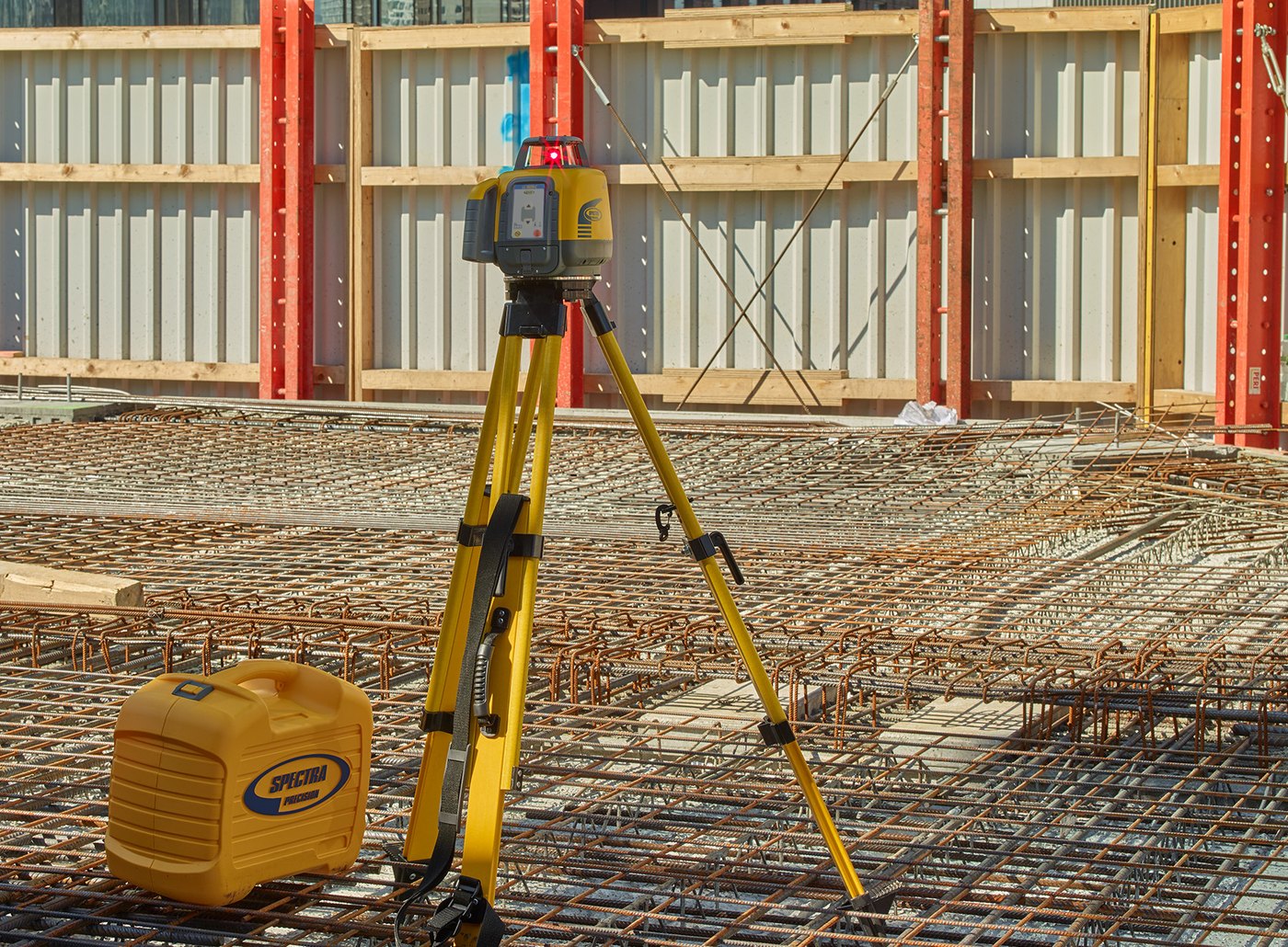 Spectra Precision LL1505C rotary laser on a tripod beside steel-reinforced concrete formwork, holding elevation for a wall pour