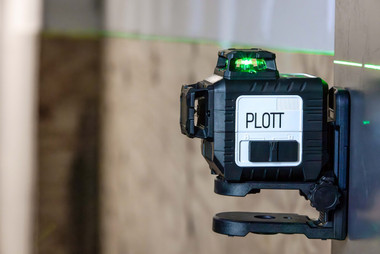 Plott PLL30-G mounted on bracket with green horizontal beam across wall surface in interior construction setting