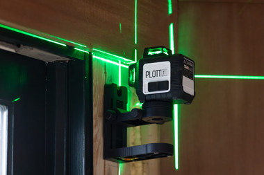 Plott PLL30-G on wall bracket projecting green laser beams across brick construction wall background