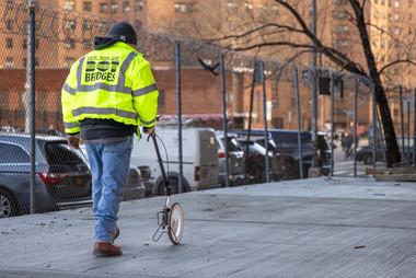 Contractor with Plott Carta measuring wheel rolling through city job site