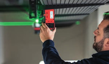 Leica RGR 300-D line laser receiver detecting a green laser line on a ceiling installation