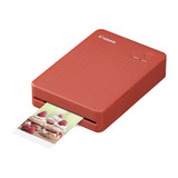 Red Canon Selphy QX20 printer with photo emerging, Canon logo on top, compact portable design.