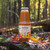 A bottle of Smart Juice Apricot Peach placed upon a rock in an autumn forest setting.
