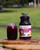 A bottle of Berry Beet on a table, next to a glass of it with ice outdoors on a sunny day
