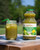 A bottle of Super Greens and a glass of it with ice on a small table