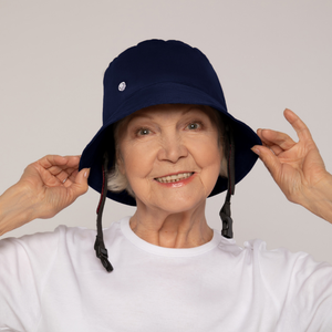 PICTURE OF AN OLDER WOMAN HANDLING A BLUE RIBCAP BLUE PROTECTIVE HELMET/HAT WITH CHIN STRAPS, BUCKET HAT STYLE