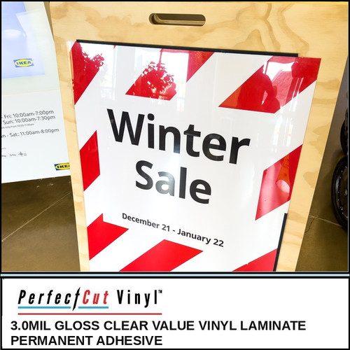 PerfectCut Vinyl 3.0mil gloss clear value vinyl laminate with permanent adhesive, shown protecting a red and white "Winter Sale December 21 - January 22" graphic on an A-frame sign.