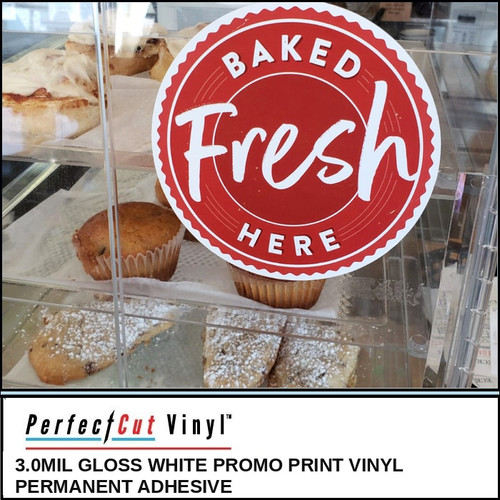 PerfectCut Vinyl 3.0mil gloss white promo print vinyl with permanent adhesive, shown as a round red "Baked Fresh Here" decal on a bakery display case filled with muffins and pastries.