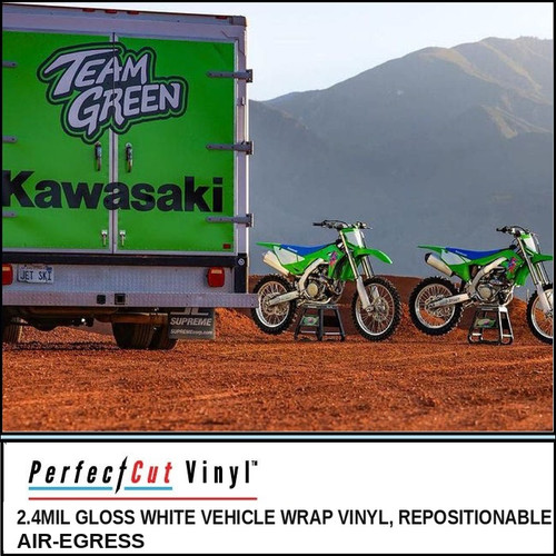 PerfectCut Vinyl 2.4mil gloss white vehicle wrap vinyl with repositionable air-egress adhesive, shown as a green box truck wrap parked on a dirt lot beside two motocross bikes with mountains behind.
