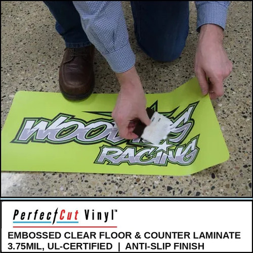 Installer squeegeeing a printed "Woody's Racing" floor graphic protected with PerfectCut Vinyl 3.75mil Embossed Clear Floor & Counter Laminate on a terrazzo floor
