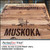 PerfectCut Vinyl 3.0mil gloss clear print vinyl with permanent adhesive, shown as a branded "Muskoka Est. 1996" logo graphic applied directly to a wood-grain restaurant table surface.