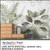 PerfectCut Vinyl 3.4mil matte white wall graphic vinyl with removable adhesive, shown applied as a tropical botanical wallpaper mural featuring green palm fronds and large leaves behind a wooden dresser styled with a vase and stacked books