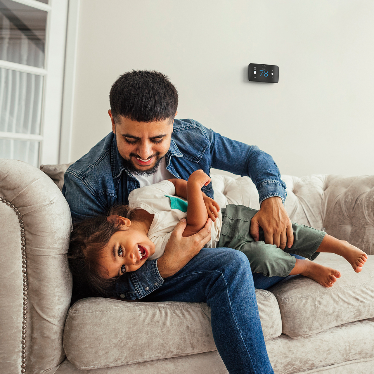 Dad and child playing with Sensi Touch 2 on wall