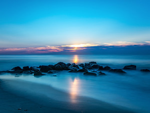 Sunrise Over A Rock Jetty On The Beach